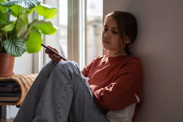 Upprörd Orolig Tonåring Flicka Läser Meddelande Smartphone Sitter Golvet Hemma — Stockfoto