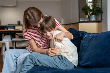 Aile eğlencesi. Mutlu anne çocuğu kucaklarken evde birlikte vakit geçirirken anne ve çocuk, oturma odasında kanepede otururken gülüyor ve eğleniyorlar. Bekar annelerin mutluluğu.