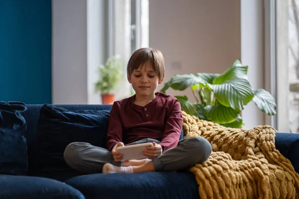 소년은 집에서 쉬면서 모바일 게임을 아이는 소파에 스마트폰을 있습니다 휴대폰 — 스톡 사진