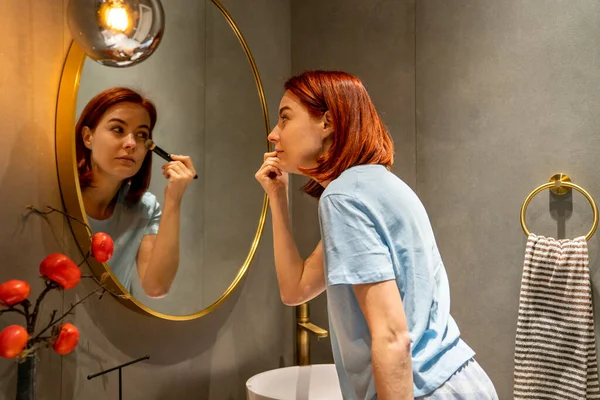 Focado Mulher Beleza Com Cabelos Vermelhos Olha Para Espelho Banheiro — Fotografia de Stock