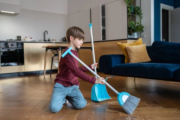 リビングで床を掃除する小さな男の子 毎日定期的な家事をしている子供 家の周りの親を助け 重要なライフスキルを得る 子供と家事の概念 — ストック写真