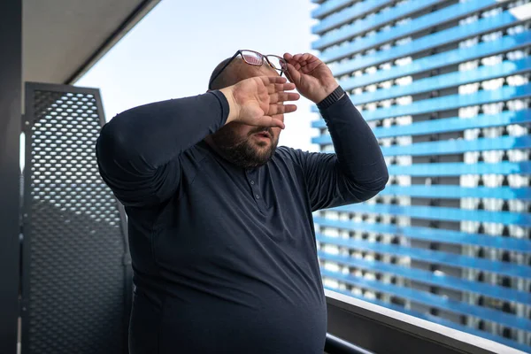 stock image Overweight problem. Unhealthy heavy man touch forehead feeling blood pressure from heat weather. Exhausted tired fat male with increased perspiration standing on balcony to difficult breathe air