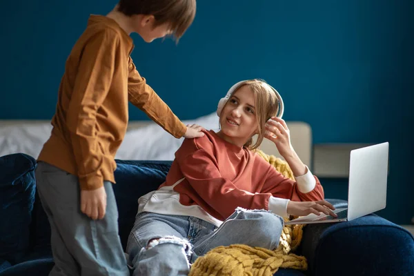 Nieuwsgierig Broertje Leidt Tienermeisje Zittend Bank Hoofdtelefoon Met Laptop Zorgzame — Stockfoto