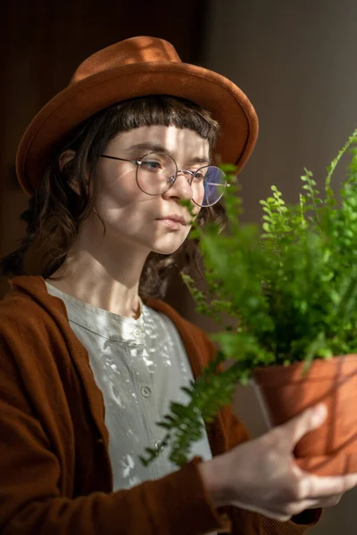 stock image Plant lover. Hipster girl holding potted fern houseplant at home, looking at foliage. Millennial woman taking care of indoor plants. People and home gardening concept