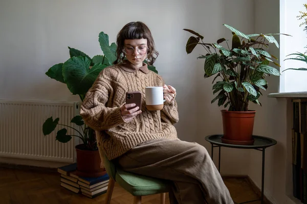 Avslappnad Tusenårig Kvinna Sitta Med Mugg Ser Kaffe Mobiltelefon Njuta — Stockfoto