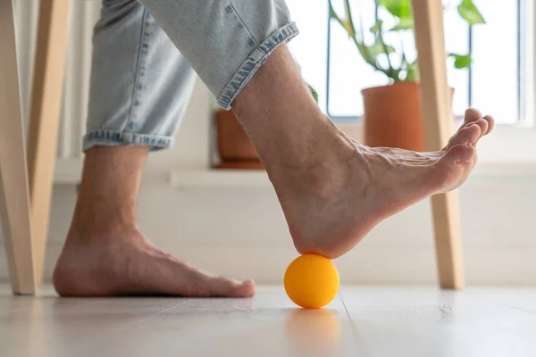 リラックスしてストレスを軽減するために足の血液循環を改善し 足の下に小さなシリコーンボールを転がす男のクローズアップ リモートワーカーのためのセルフマッサージ — ストック写真