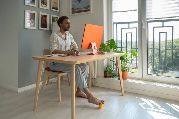 Joven Freelancer Usando Masajeador Pies Mientras Está Sentado Frente Computadora — Foto de Stock