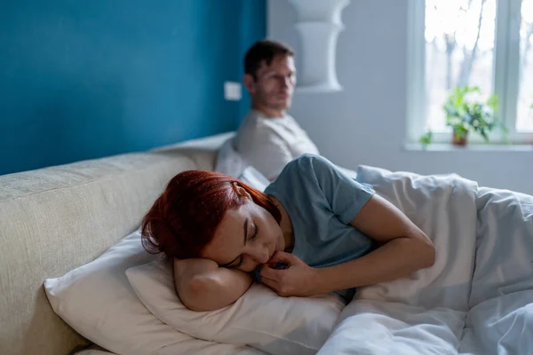 Sad offended woman after quarrel with boyfriend in bedroom. Difficult relations family conflict. Depressed female lies on edge of bed separated from man husband after argument of hard conversation.