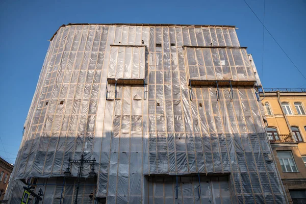 建物の正面のオーバーホール 塵および構造の破片に対する家の保護プラスチック フレーム 市の中心部に歴史的建造物の一般的な再建 エクステリアの建設工事 — ストック写真