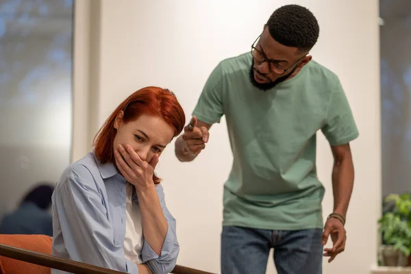 Nervous angry husband African American man screaming try to explain prove something to hysterical stressed European woman wife. Diverse family couple have home conflict. Abuse, psychological pressure
