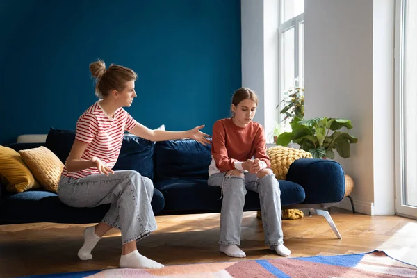 Conflict between parent and teenage. Teen girl sitting on sofa ignoring toxic mother scolding child. Not understanding between daughter and nervous mother, problems in family
