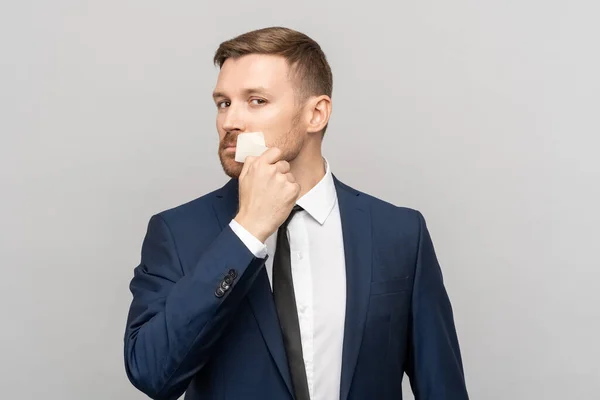 Confident man rips duct tape from sealed mouth. Concept about freedom of speech, equality, democracy against infringement of human rights, vote. Convinced businessman on studio grey background