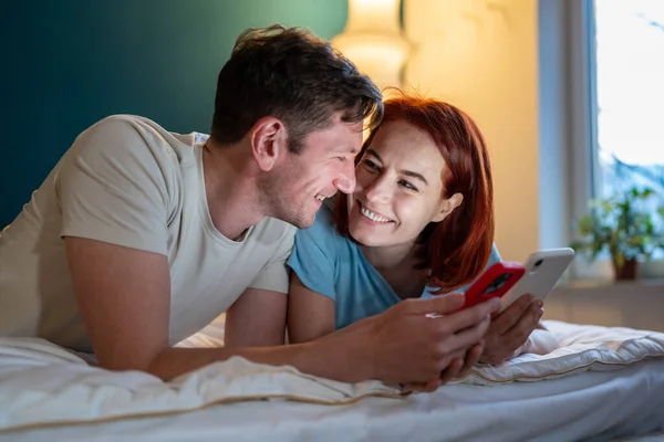 Ett Par Kära Leenden Liggandes Sängen Med Smartphones Lycklig Kvinna — Stockfoto