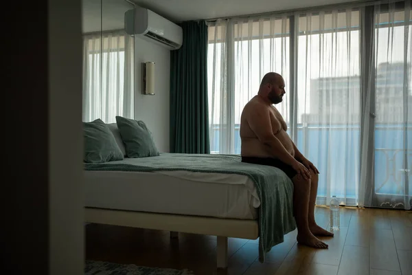 Nadváha Depresivní Nudný Muž Kraťasech Sedí Posteli Hotelovém Pokoji Zavřenýma — Stock fotografie