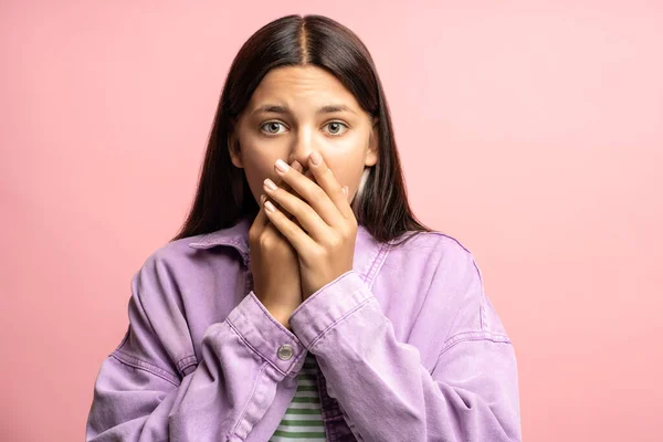 stock image Amazed shocked teenage girl looking at camera covering moth with hands feeling fear, astonishment. Negative wow face expression on pink background. Advertising, sale, discount banner, poster concept.