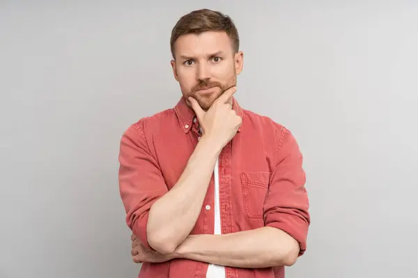 stock image Pensive puzzled thoughtful man looking at camera touching chin isolated background. Embarrassed guy feeling confusion solves problems, struggling with choice. Haughty caucasian male pondering idea.