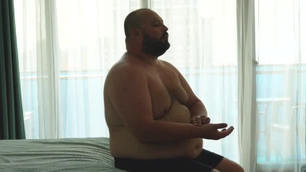 太りすぎの男性は手の脈拍を測定し ベッドに座っている発作中に呼吸演習を行います 呼吸困難 ポストコビド合併症 過剰な体重の人々の健康問題コンセプト — ストック動画