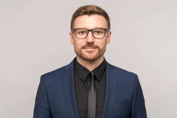 stock image Smiling successful confident businessman in suit glasses looking at camera on grey background. Man entrepreneur on advertisement poster with copy space. Business portrait, positive office worker.