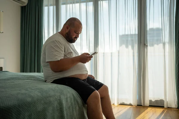 Overweight Guy Hanging Smartphone Resort Sitting Bed Hotel Room Vacation — Stock Photo, Image