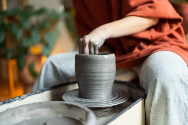 Craftswoman ceramist hands sculpt wet clay form final handmade product on pottery wheel for order. Involved person create unique tableware to relieve stress restore mental health on workshop after job