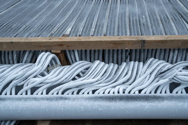 Close up of flexible refrigerated hoses filled with frozen water. Modern engineering system for skating rink cooling. Maintenance, preparation and installation of outdoor skating rink for winter