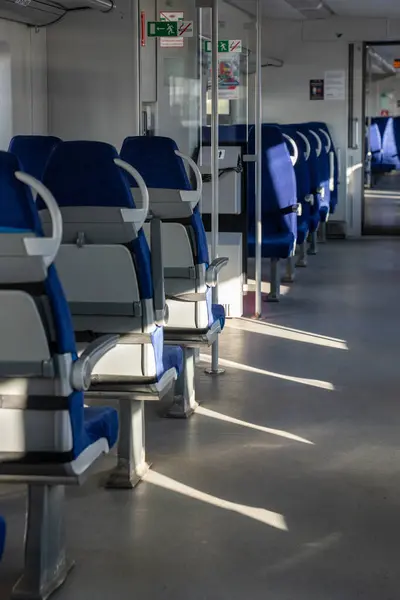 Interior of modern passenger high-speed express train, row of empty blue fabric soft seats selective soft focus. Inside the train carriage with comfortable and colorful chairs. Public transportation