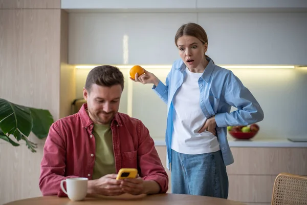 嫉妬をコントロールする妻は 携帯電話で夫のメッセージを読みます 忠誠心不信 婚姻不和の概念 自宅のキッチンで屋台のスマートフォンで背後に立っている驚くべきショックを受けた女性 — ストック写真