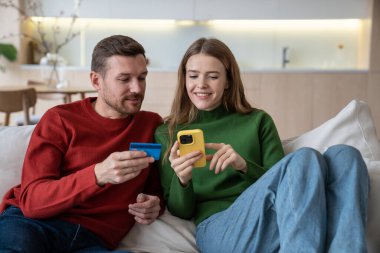 Memnun aile çiftimiz online ödemeleri akıllı telefondan kartla yapıyorlar. Keyifli kadın ve erkek biletlerini evdeki kanepede oturarak alıyor. İnternet alışverişi telefonla mal seçer