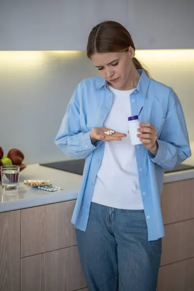 stock image Anxious alarmed woman hypochondriac taking pills dietary supplements antidepressants tranquilizers at home. Worried young female has lots of medications standing on kitchen. Preventive treatment cure.