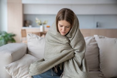 Depresyondaki mutsuz kadın ekoseye sarılmış, titriyor, hasta, hasta, yüksek ateşi olan. Grip belirtilerinden muzdarip bir kadın, iltihap, mevsimsel virüs evde vakit geçiriyor.