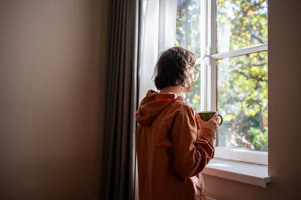 Samotny Nastolatek Stojący Przy Oknie Patrzący Słoneczną Letnią Pogodę Smutkiem — Zdjęcie stockowe