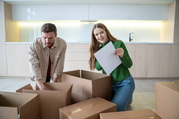 Happy wife husband unpacking boxes after moving to new apartment checking the list. Start of marriage, family life, living together. Relocation marriage buying real estate apartment, mortgage concept.