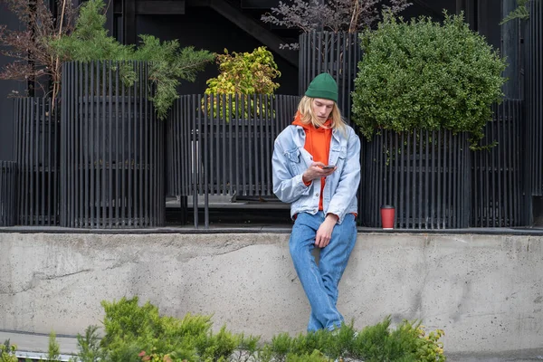 Pensive Trendy Stylový Hipster Chlap Sedí Betonové Bariéře Drží Smartphone — Stock fotografie