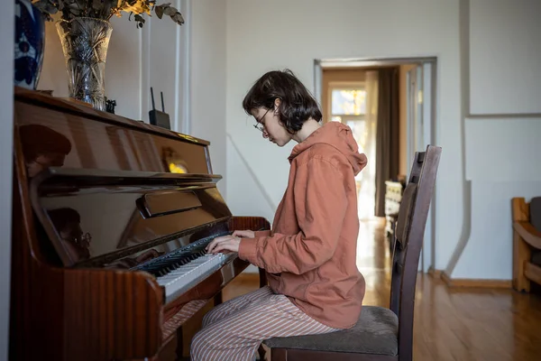 stock image Focused girl sitting on chair, playing piano, improvising practicing skills at home lesson, learning instrument notes, performing classical music for meditation, relaxation, as sound therapy and hobby