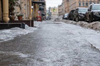 Slippery sidewalk in the city. Pavement covered with slippery ice selective soft focus. Frozen rain. Winter time.  clipart