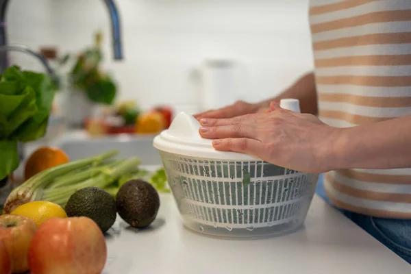 stock image Preparing of useful, fresh, healthy vegan home dinner, snack of fruit and vegetables. Drying of greens spinach in plastic hand food centrifuge. Natural ingredients full of vitamins for detox, slimming