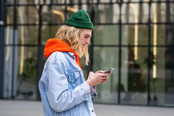 感兴趣的斯堪的纳维亚嬉皮士男人站在外面看手机回复女朋友的留言 快乐的年轻人 带着手机等着他的朋友在街上滚动社交媒体 — 图库照片