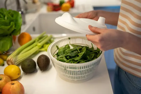 stock image Preparing of useful, fresh, healthy vegan home dinner, snack of fruit and vegetables. Drying of greens spinach in plastic hand food centrifuge. Natural ingredients full of vitamins for detox, slimming