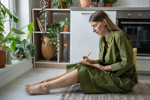 Focada Mulher Atenta Escrita Diário Pessoal Sentado Chão Cozinha Casa — Fotografia de Stock