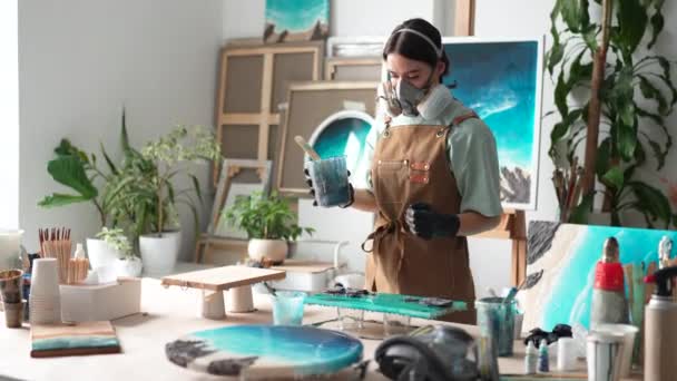 Seniman Wanita Terkonsentrasi Dalam Masker Respirator Memeriksa Lukisan Setelah Menuangkan — Stok Video