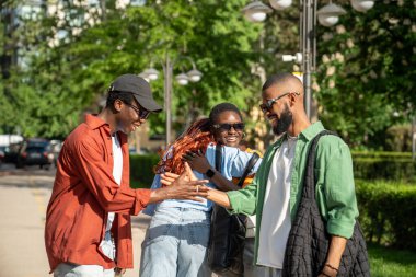 Afro-Amerikan dostlarımızın keyifli bir selamı var. Neşeli siyah öğrencilerden oluşan mutlu bir grup birlikte vakit geçirmek için birbirlerine sarılıyorlar. İki erkek tokalaşıyor, kızlar gülümsüyor, birbirlerini görüyorlar.