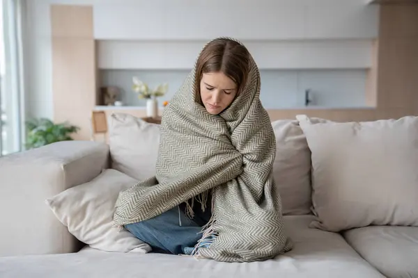 stock image Desperated depressed woman crying sitting on couch with closed eyes wrapped in plaid. Girl suffering fom emotional pain having life troubles problems. Mental disorder, anhedonia, stress, sleepiness.