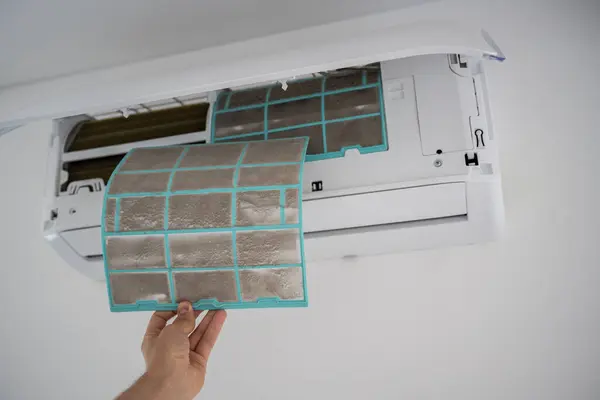 stock image Person removing dirty dusty air conditioner coarse filter for washing, cleaning. Home air conditioner service maintenance, repair and clean equipment. Dust - cause of illness. Closeup.