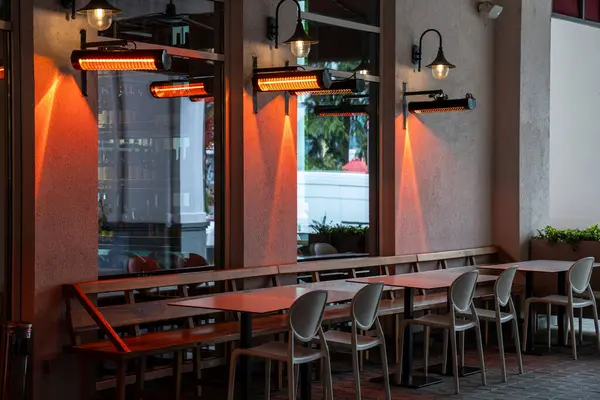 stock image Outdoor cafe equipped with heaters positioned on walls for comfortably warming customers guests from above. Dining spot with radiators, cozy restaurant with opportunity to lunch outside open-air