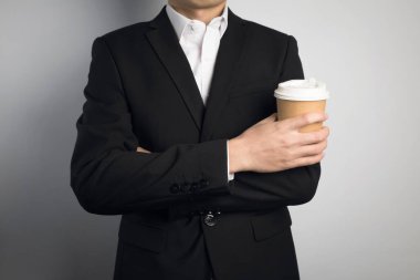 Elinde kağıt bardak tutan bir iş adamı.
