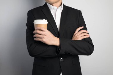 Elinde kağıt bardak tutan bir iş adamı.