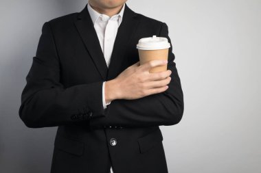 Elinde kağıt bardak tutan bir iş adamı.