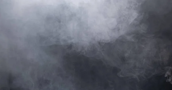 白い煙と黒い背景の霧の濃いふわふわのパフ 抽象的な煙雲 動きが焦点からぼんやりとした 空気中でなびくドライアイスフライから煙が吹く 効果的なテクスチャ — ストック写真