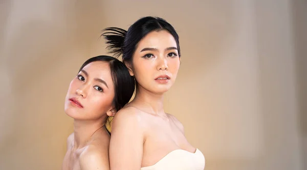 Portrait Face shot two Beautiful young Asian women with fashion cosmetic make up clean skin on yellow beige background isolated. Vintage Fashion makeup skincare together, copy space