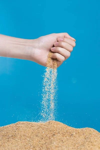 stock image Hand releasing dropping sand. Fine Sand flowing pouring through fingers against blue background. Summer beach holiday vacation and time passing concept. Isolated high speed shutter